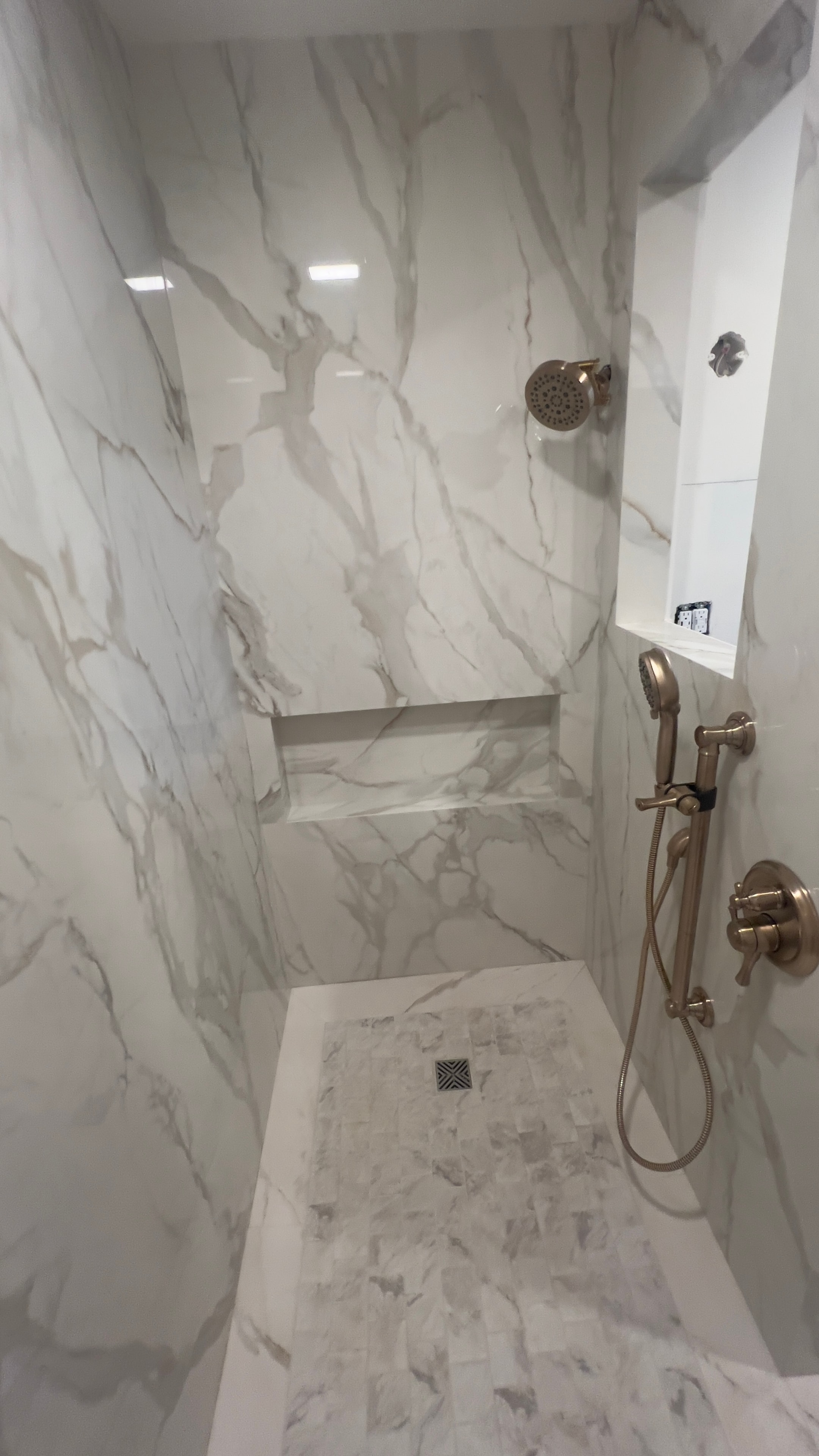 Custom marble shower with brushed gold fixtures, built-in bench, and decorative glass panel trim — GT Home Solution design build in Amador County, CA